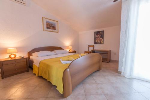 a bedroom with a large bed with a yellow blanket at Stella Maris Accommodation in Klenovica