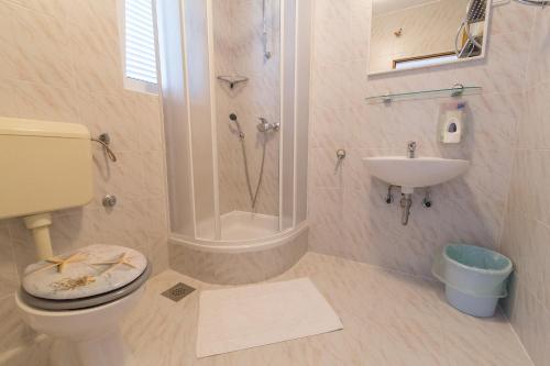 a bathroom with a shower and a toilet and a sink at Stella Maris Accommodation in Klenovica