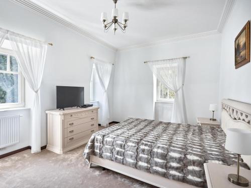 a white bedroom with a bed and a tv at Apartment Villa Dionysus in Karlovy Vary