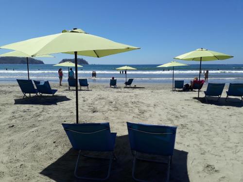 a group of chairs and umbrellas on a beach at Las Perlitas Rentals Playa Samara in Sámara