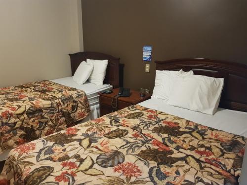 a hotel room with two beds and a night stand at Hotel Florencia in San Miguel