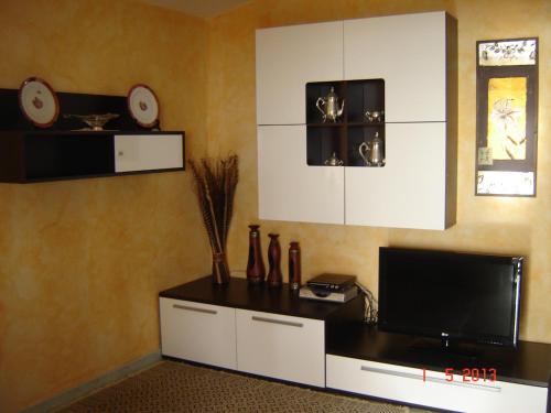 een woonkamer met een tv en witte kasten bij casa giafra in S'archittu Cuglieri
