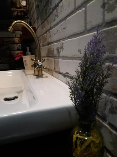 a bathroom sink with a vase with purple flowers in it at Traditional Guesthouse in Tríkala