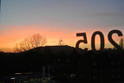 a view of the sun setting over a hill with a house at Chillten Bottrop in Bottrop