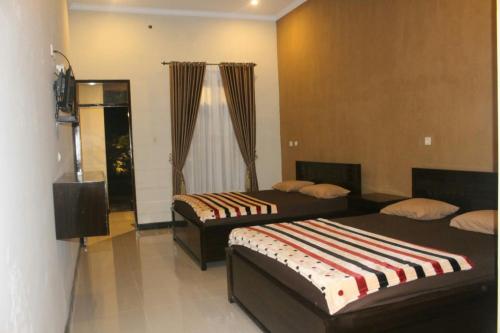 um quarto com 2 camas e uma televisão em Sederhana Homestay em Batukaras
