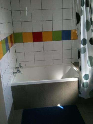 a bath tub in a bathroom with colorful tiles at Coronation Park Holiday Park in Ashburton