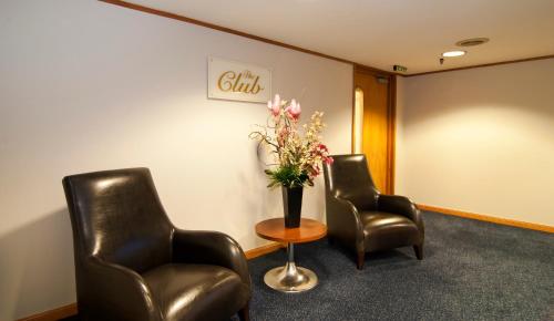 a waiting room with two chairs and a vase of flowers at Millennium Hotel Rotorua in Rotorua