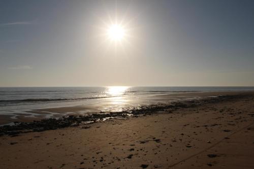 a beach with the sun rising over the ocean at Au Petit Bonheur in La Tranche-sur-Mer