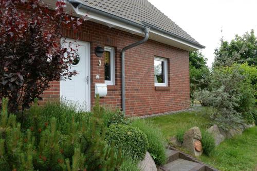 ein Backsteinhaus mit einer weißen Tür und einem Hof in der Unterkunft Ferienhaus 8erwassereck in Ückeritz