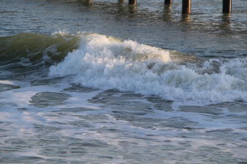a small wave in the ocean near a pier at Au Petit Bonheur in La Tranche-sur-Mer