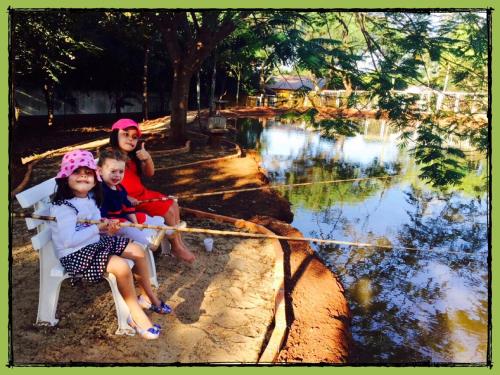a family sitting on a bench in front of a pond at Villa Verde Hotel in Avaré
