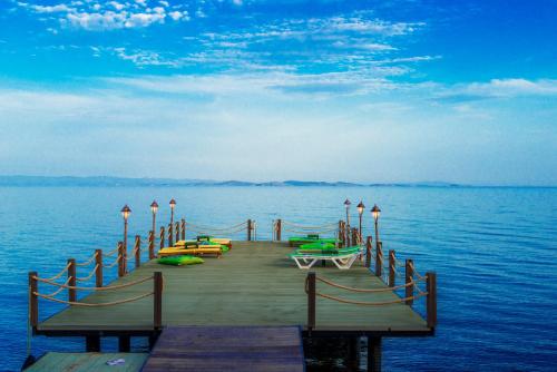 a wooden dock with boats on the water at Kayalar Blue Beach Hotel in Sazlı