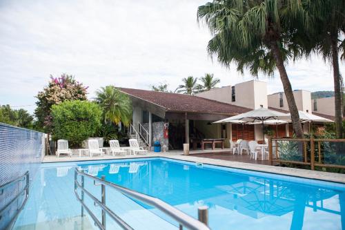 - une piscine avec des chaises et une maison dans l'établissement Pousada Sol e Mar, à Juqueí