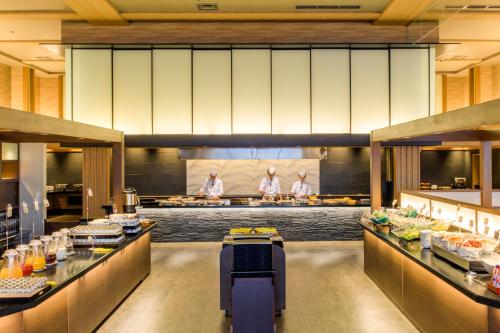 a restaurant with three chefs preparing food in a kitchen at Inatori Ginsuiso in Higashiizu