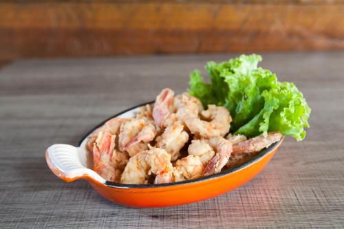 an orange bowl of shrimp and lettuce on a table at Pousada Sol e Mar in Juquei