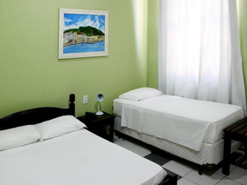 a bedroom with two beds and a picture on the wall at Kontiki Hotel in São Francisco do Sul