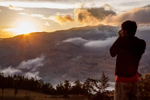 a man standing on a hill looking at the sunset at Community Hostel Alausi in Alausí