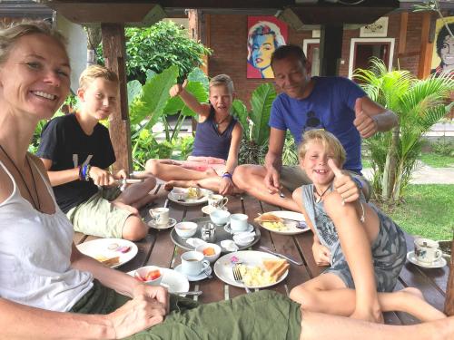 un gruppo di persone sedute attorno a un tavolo che mangiano cibo di Griya Pasir Ukir a Sanur