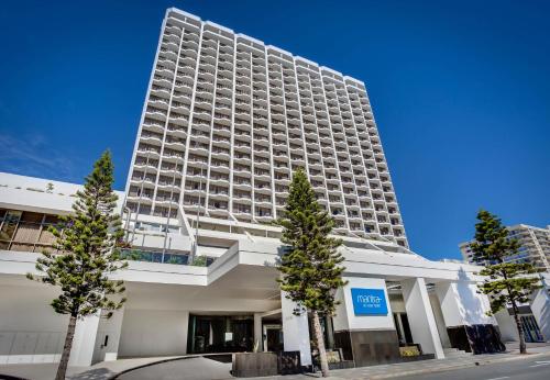 a tall white building with trees in front of it at Mantra on View Hotel in Gold Coast