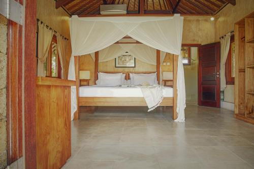 a bedroom with a bed with a canopy at Three Monkeys Villas in Uluwatu