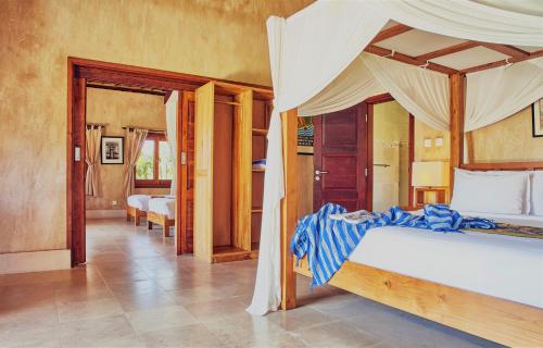 1 dormitorio con 1 cama con dosel en Three Monkeys Villas en Uluwatu