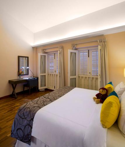 a large white bed with a teddy bear sitting on it at Park Avenue Robertson in Singapore