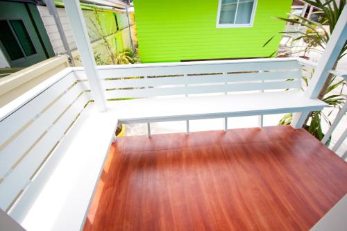 a porch with a white bench on a green house at Bannrommai Sattahip in Sattahip