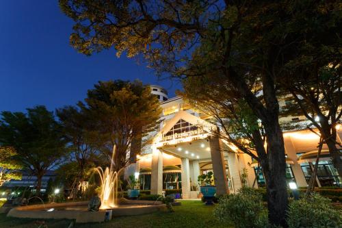 a building with a fountain in front of it at night at Surin Majestic Hotel in Surin