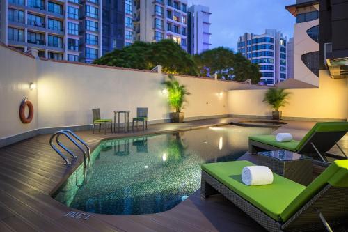 a swimming pool with chairs and a table on a building at Park Avenue Robertson in Singapore