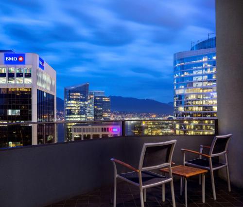 a balcony with two chairs and a city skyline at night at Hyatt Regency Vancouver in Vancouver