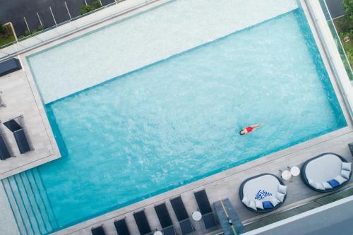an overhead view of a swimming pool with a person in the water at Brighton Grand Hotel Pattaya - SHA Extra Plus in Pattaya North