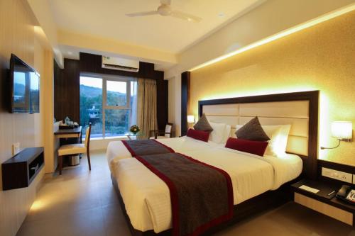 a hotel room with a large bed and a desk at Hotel Vista Inn in Navi Mumbai