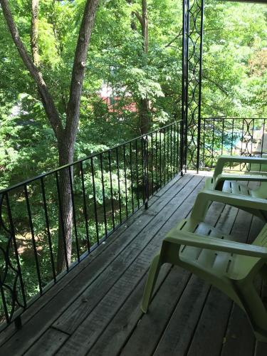 a wooden deck with a bench and a tree at The Wanderoo Lodge in Eureka Springs