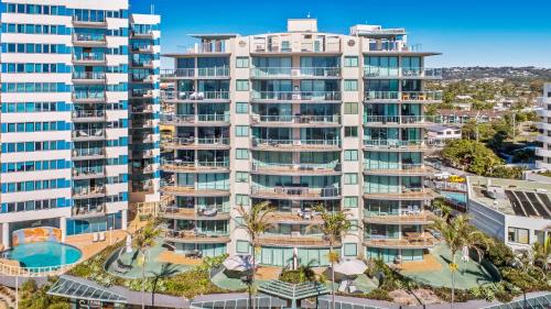 an apartment building with a pool and palm trees at Key Largo Maroochydore in Maroochydore