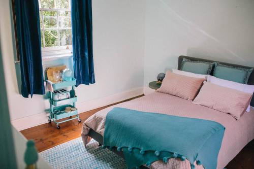 1 dormitorio con 1 cama con cortinas azules y ventana en Terroir Auburn, en Auburn