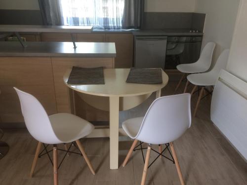 a kitchen with a table and four white chairs at Guitte family in Poilly-sur-Serein