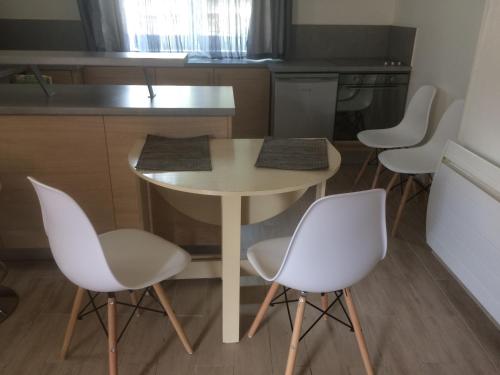 eine Küche mit einem Tisch und 4 weißen Stühlen in der Unterkunft Guitte family in Poilly-sur-Serein