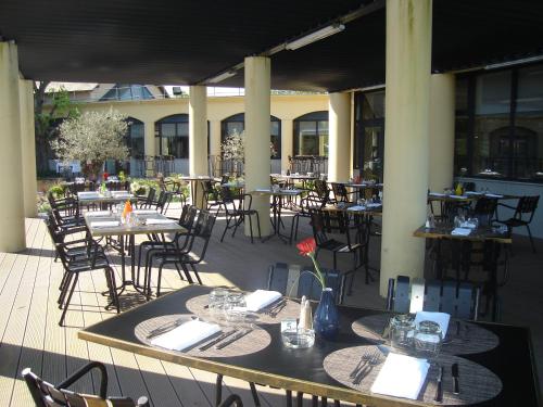 an outdoor patio with tables and chairs and tables and tablesktop at Hotel Le Paddock in Magny-Cours