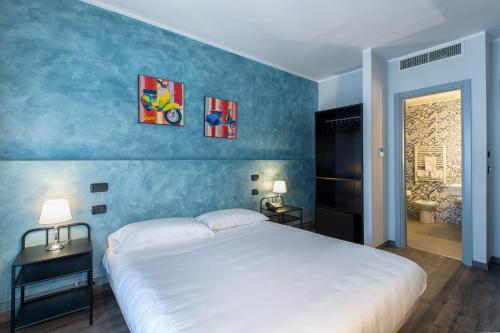 a bedroom with a white bed and a blue wall at Hotel Napoleon Susa in Susa