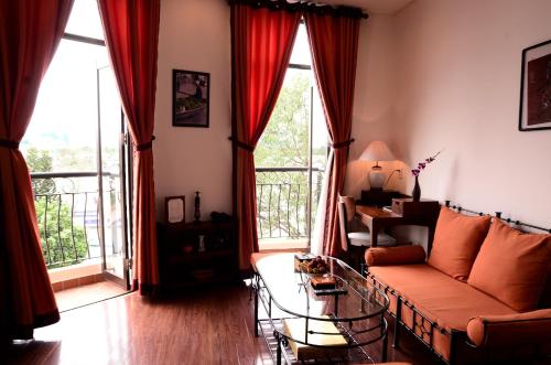 a living room with a couch and a table and windows at Nam Bo Boutique Hotel in Can Tho