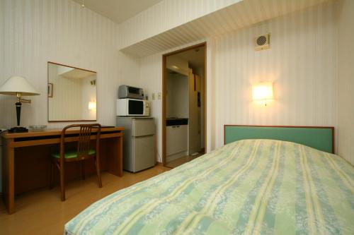 sypialnia z łóżkiem, biurkiem i kuchenką mikrofalową w obiekcie Accecss Tenjin w mieście Fukuoka