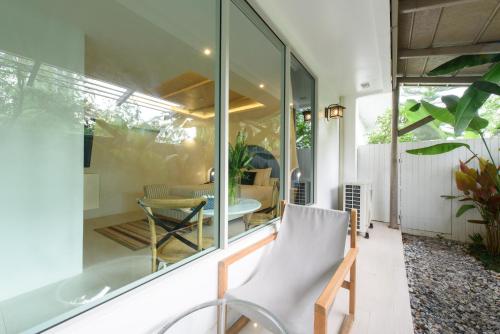 a glass house with a chair on a patio at Costa Village Bangsaray in Bang Sare