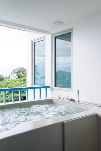 a bathtub in a bathroom with windows at Costa Village Bangsaray in Bang Sare