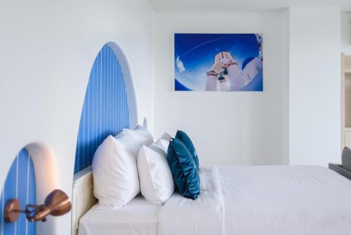 a white bed with blue and white pillows on it at Costa Village Bangsaray in Bang Sare