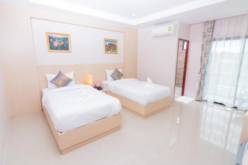 a bedroom with two beds and a window at Samrong Garden in Udon Thani