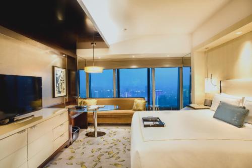 a hotel room with a large bed and a television at Fairmont Nanjing in Nanjing