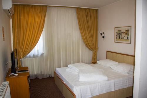 a bedroom with a bed with white pillows and a television at HOTEL T23 srl in Iaşi