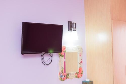 a flat screen tv hanging on a wall with a mirror at Samrong Garden in Udon Thani