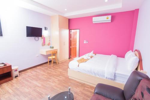 a bedroom with a pink wall with a bed and a couch at Samrong Garden in Udon Thani