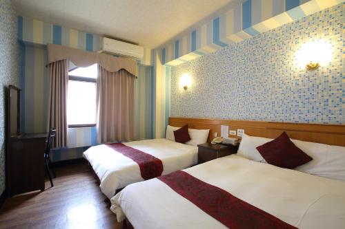 a hotel room with two beds and a window at Chiayi Crown Hotel in Chiayi City